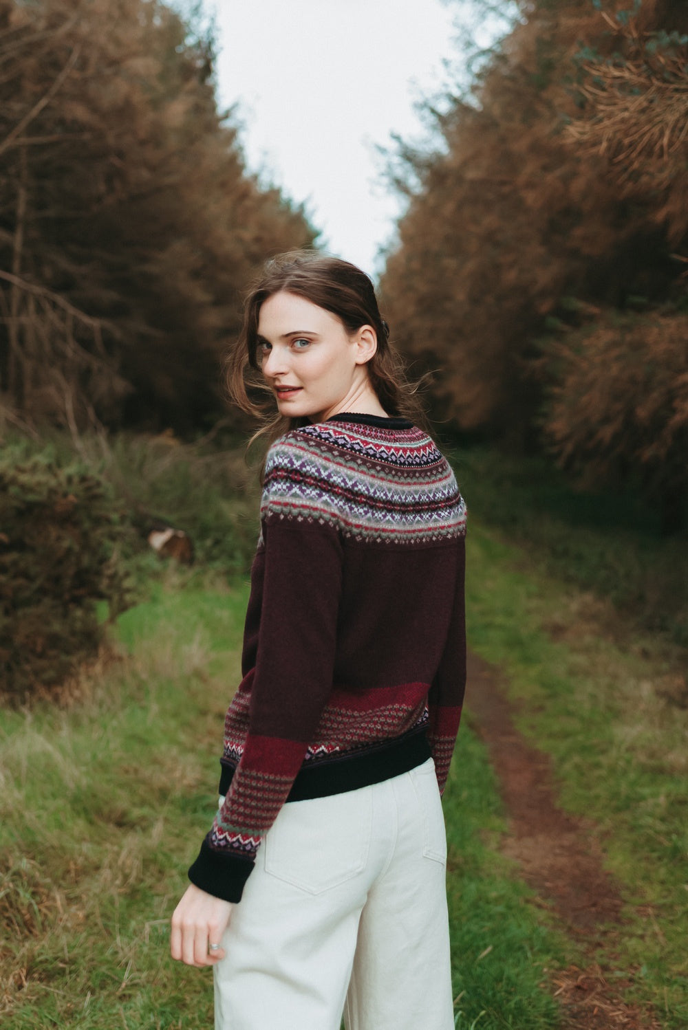 Eribé Alpine Cardigan in Tyrian, model looking back, showing the patterned shoulders