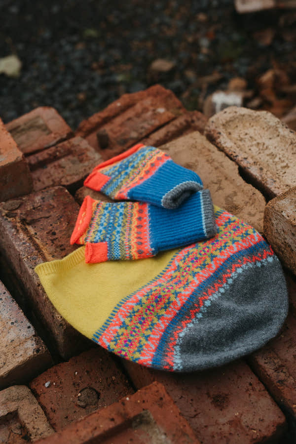 Eribé Alloa Beanie in Charm-Bonnie, hat and coordinating fingerless mitts arranged on stone