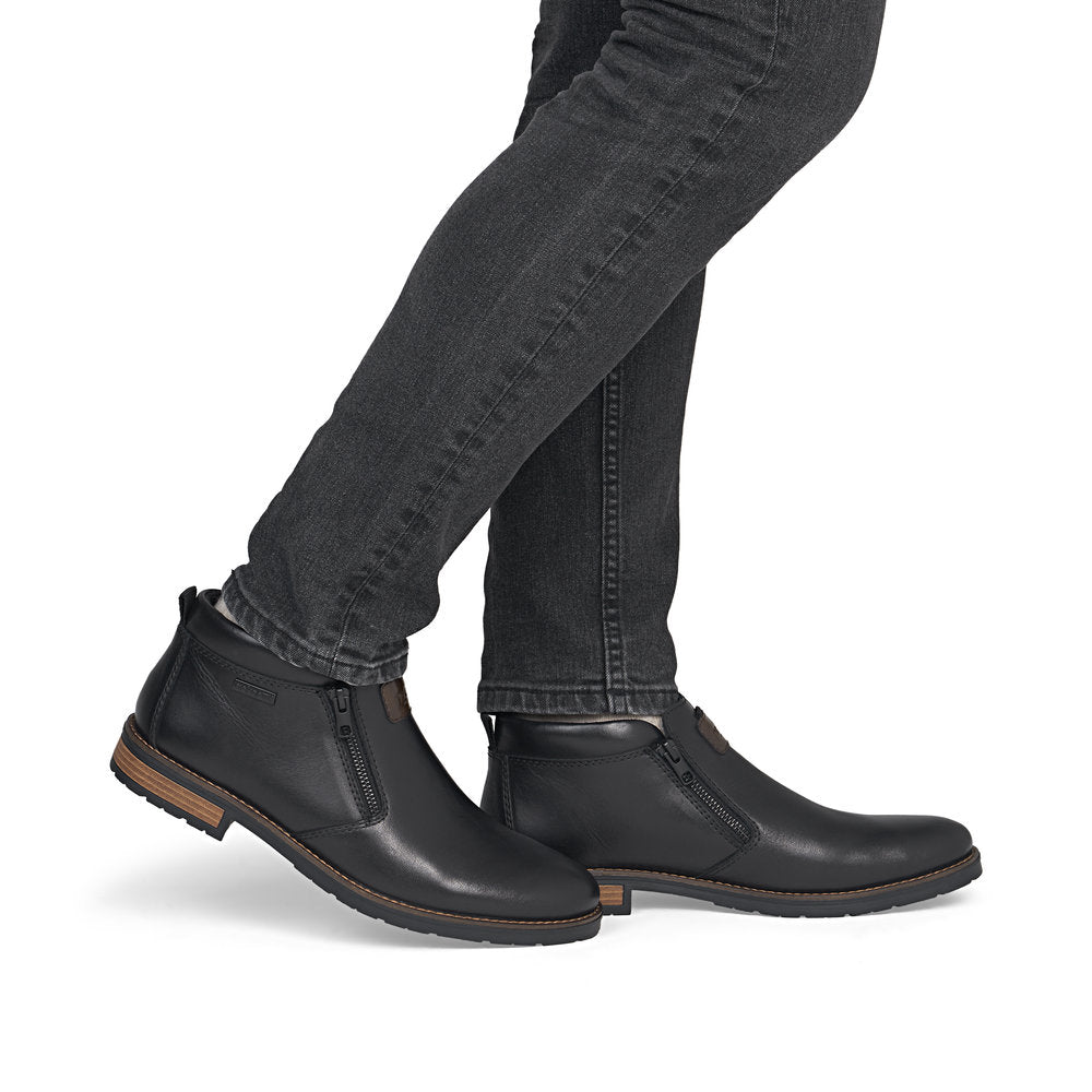 Rieker 14656-00 men's wide black leather water resistant side zip ankle boots, on-foot lifestyle view.