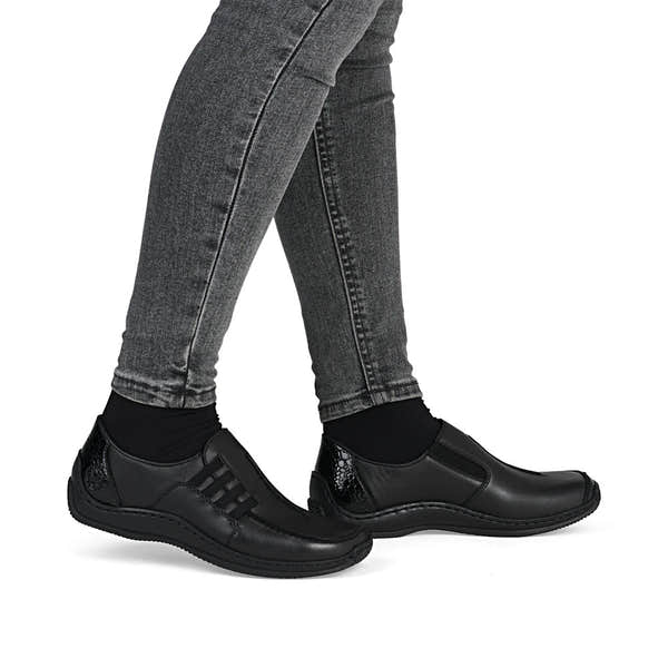 Rieker L1777-00 women's black leather slip on shoes, on-foot lifestyle view.