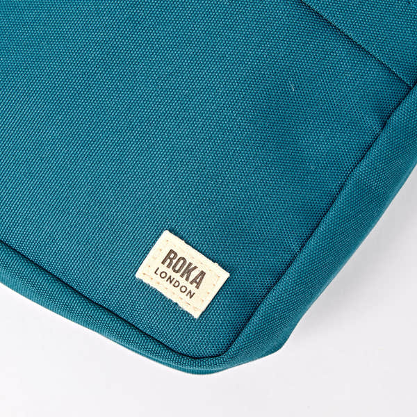 Roka Bond Deep Teal Recycled Canvas Crossbody Bag, brand label detail.