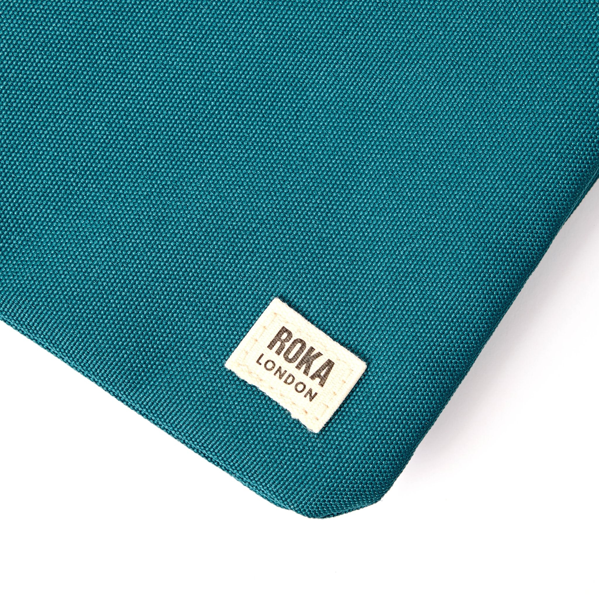 Roka Carnaby XL Deep Teal Recycled Canvas Crossbody Bag, brand label detail.