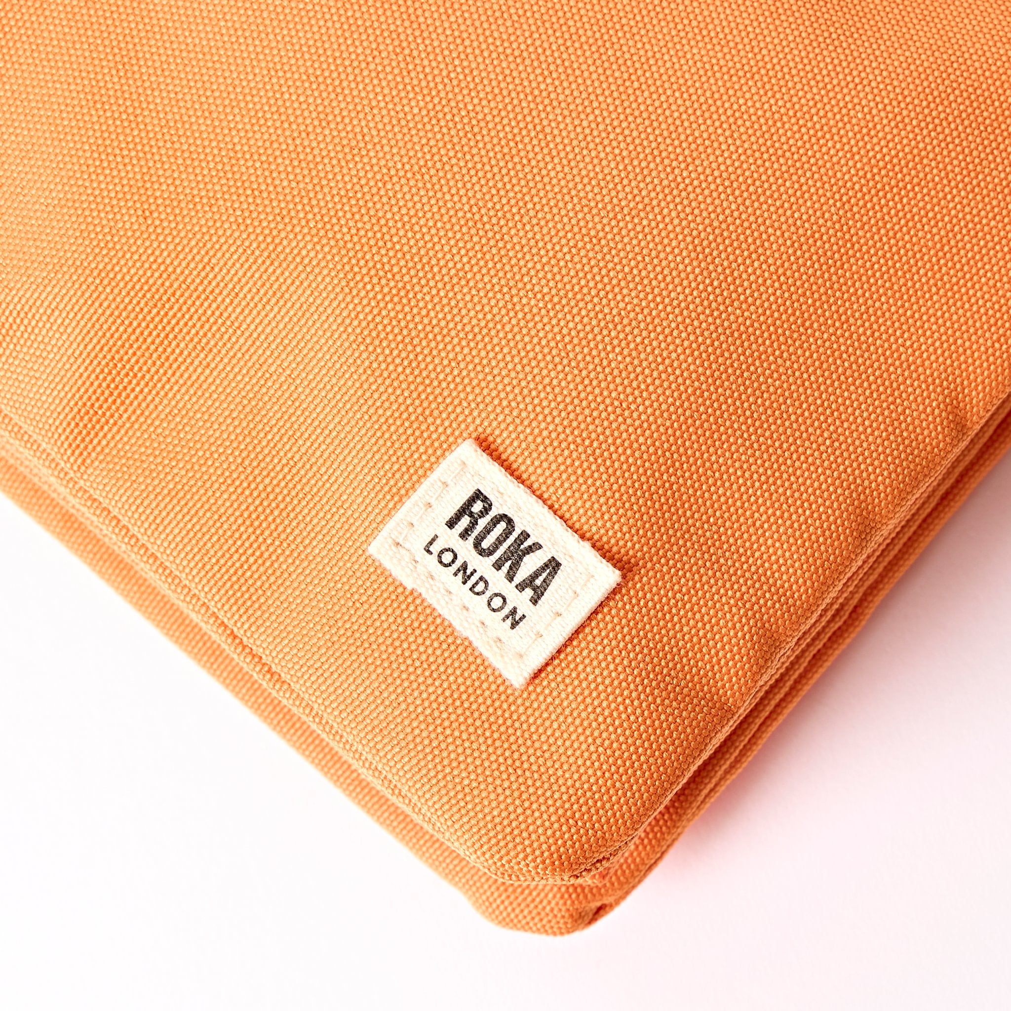 Roka Carnaby XL Jaffa Orange Recycled Canvas Crossbody Bag, brand label detail.