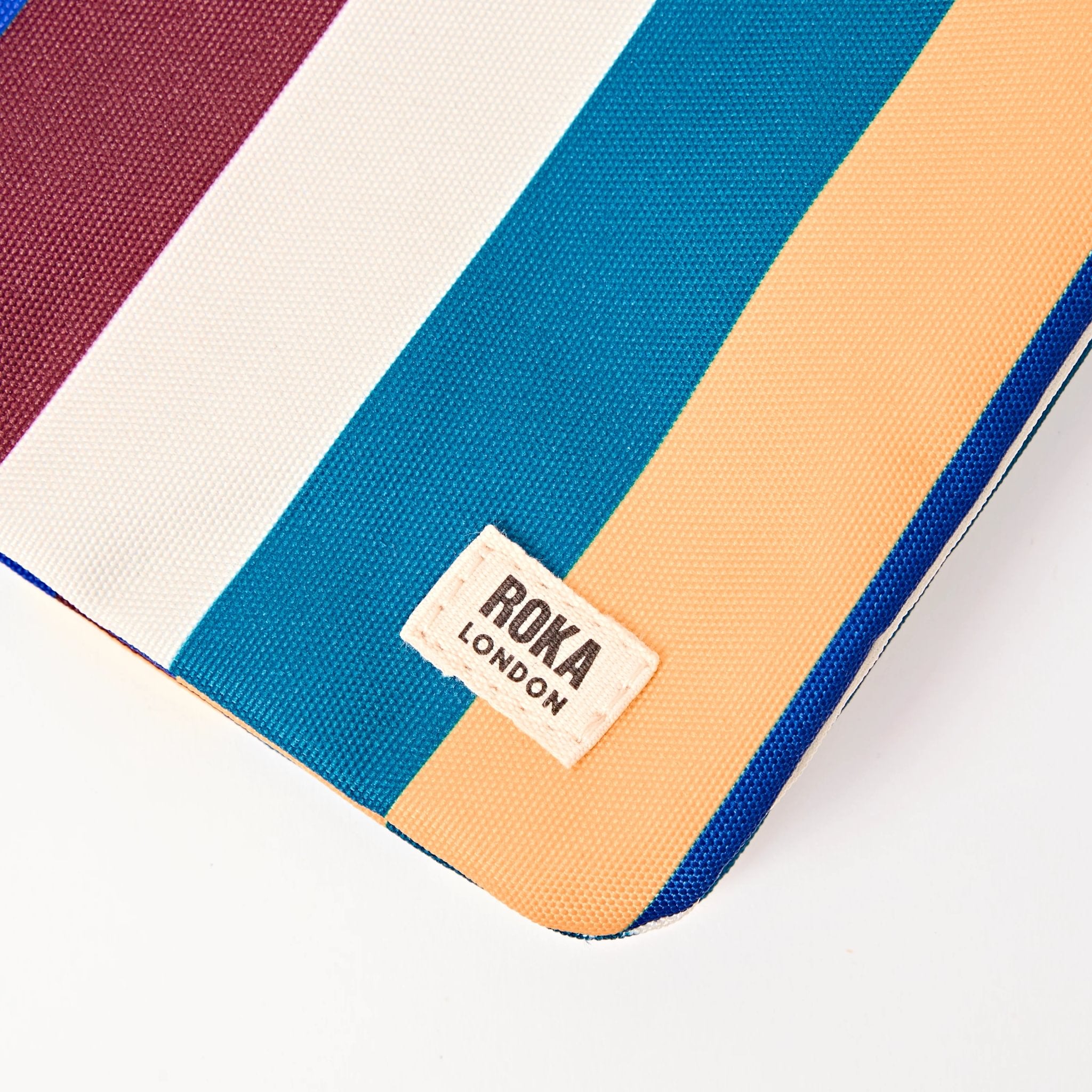 Roka Carnaby XL Wide Multi Stripe Recycled Canvas Crossbody Bag, brand label detail.