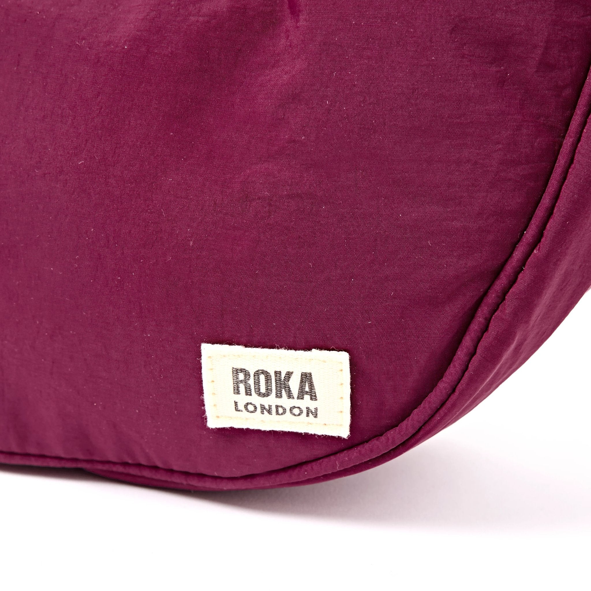Roka Farringdon Merlot Recycled Taslon Half Moon Bag, brand label detail.