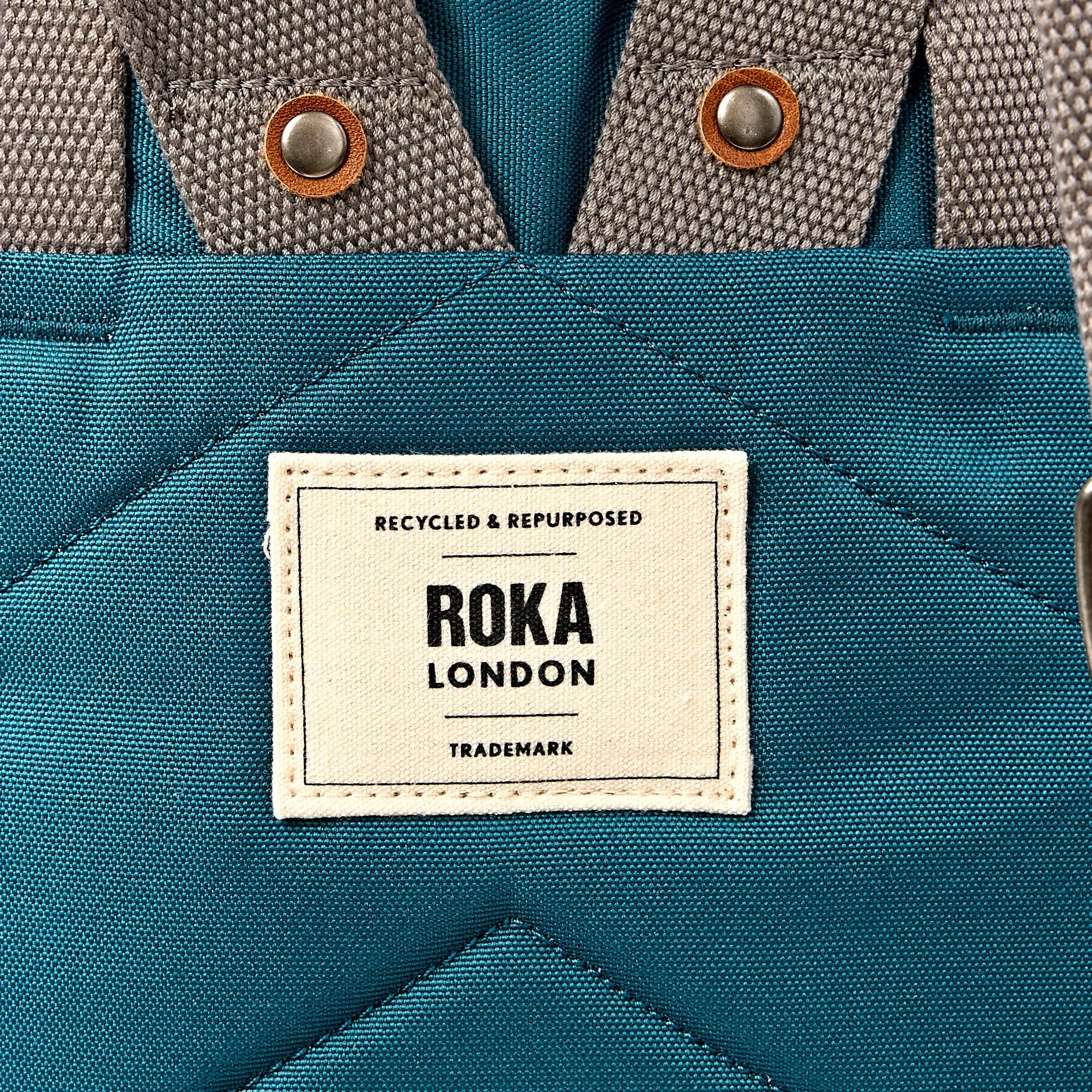 Roka Finchley Medium Deep Teal Recycled Canvas Backpack, brand label detail.