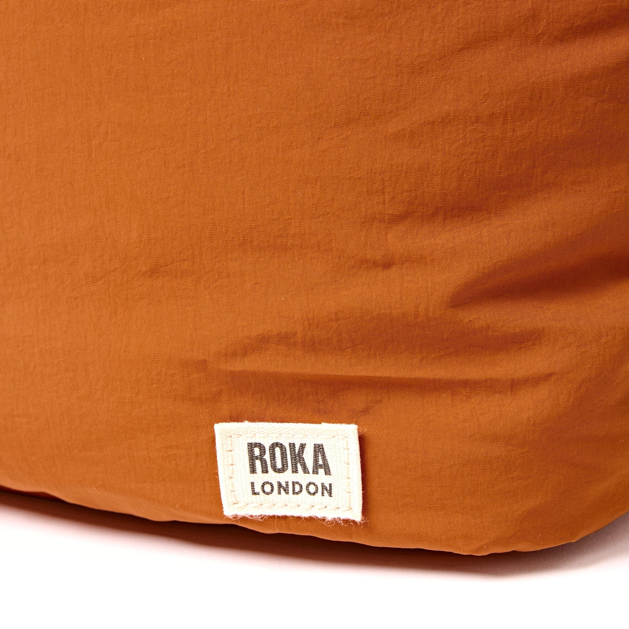Roka Oxford Dijon Recycled Taslon Shoulder Bag, brand label detail.