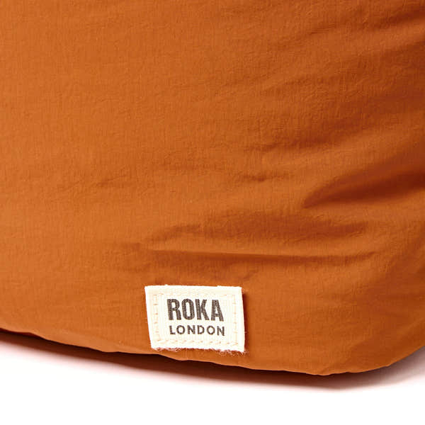 Roka Oxford Dijon Recycled Taslon Shoulder Bag, brand label detail.