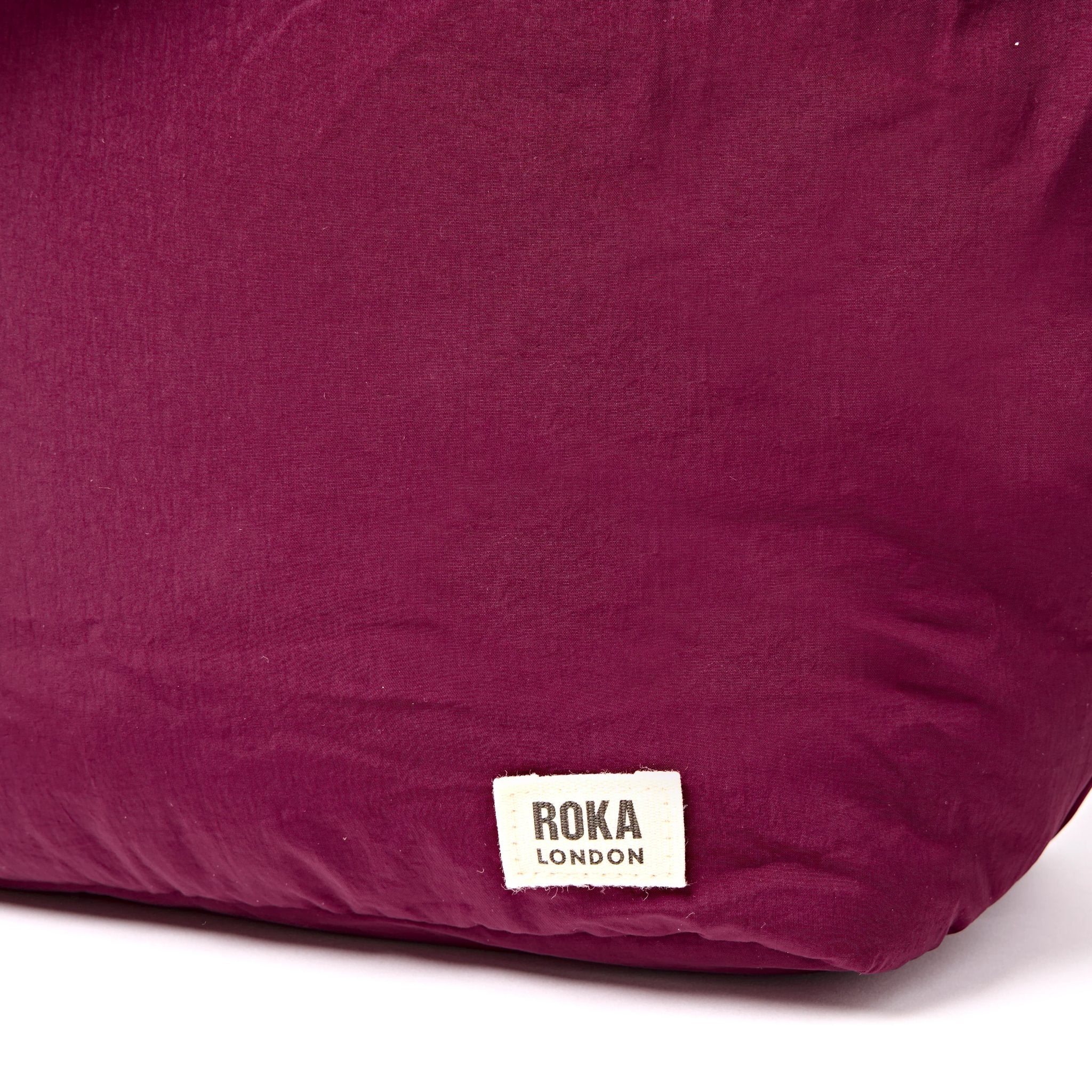 Roka Oxford Merlot Recycled Taslon Shoulder Bag, brand label detail.