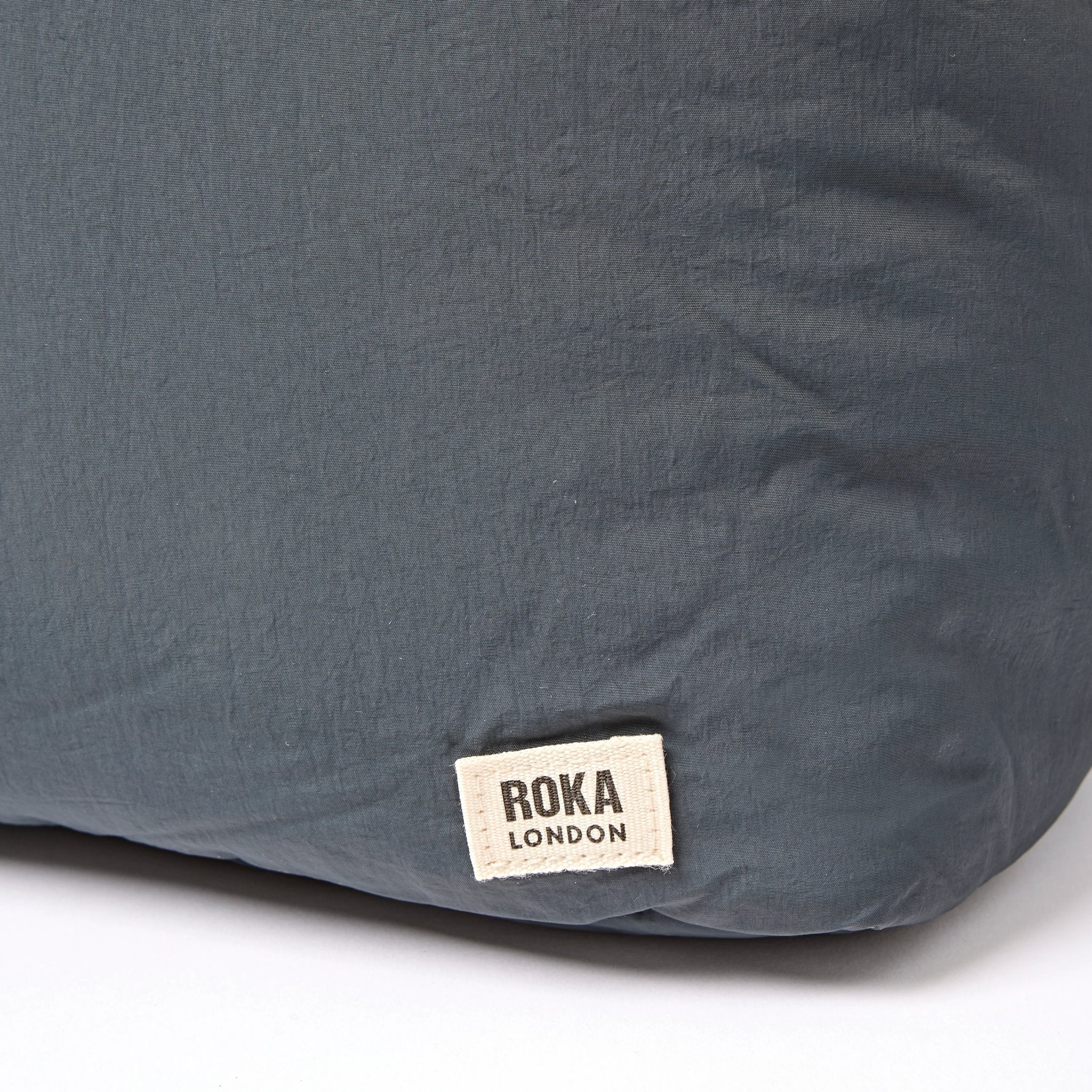 Roka Oxford Raven Recycled Taslon Shoulder Bag, brand label detail.