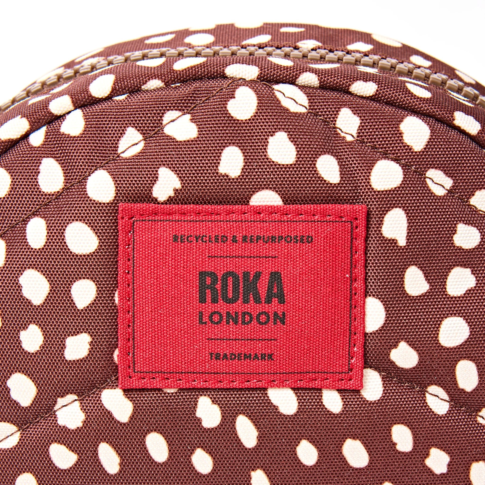 Roka Paddington Brown Dot Recycled Canvas Crossbody Bag, brand label detail.