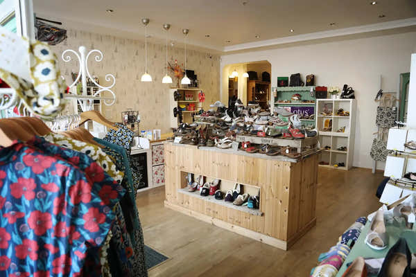 shoe shop with lots of footwear in the background and dresses in the foreground
