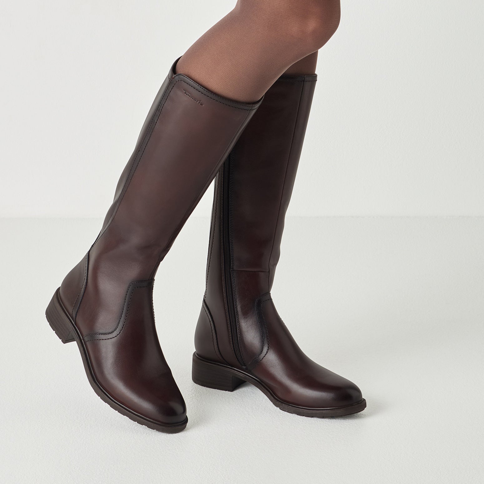 Mahogany brown tamaris knee-high boot worn on foot, side view.