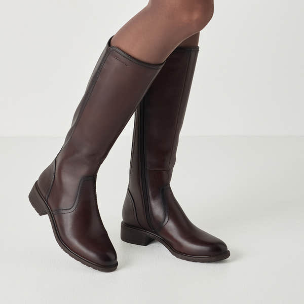 Mahogany brown tamaris knee-high boot worn on foot, side view.