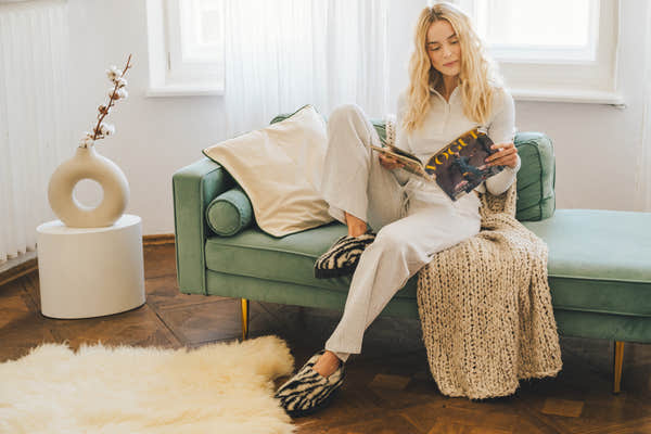 Yoko Full unisex Zebra Print wool slippers worn while reading on a sofa, lifestyle view.